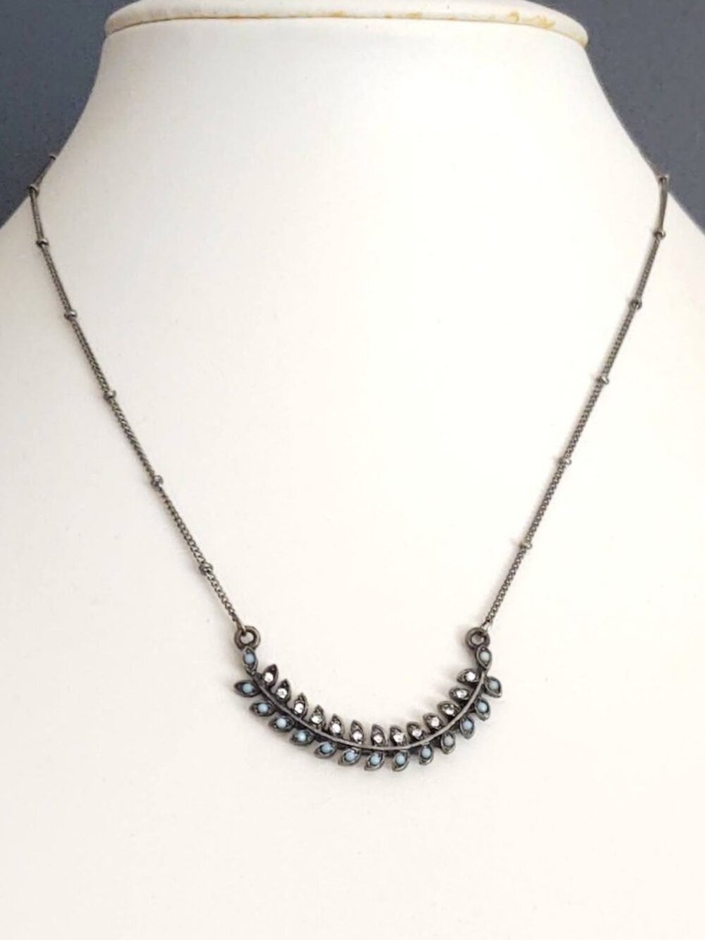 Curved dark gray metal with tiny petal design containing tiny cz and blue beads
